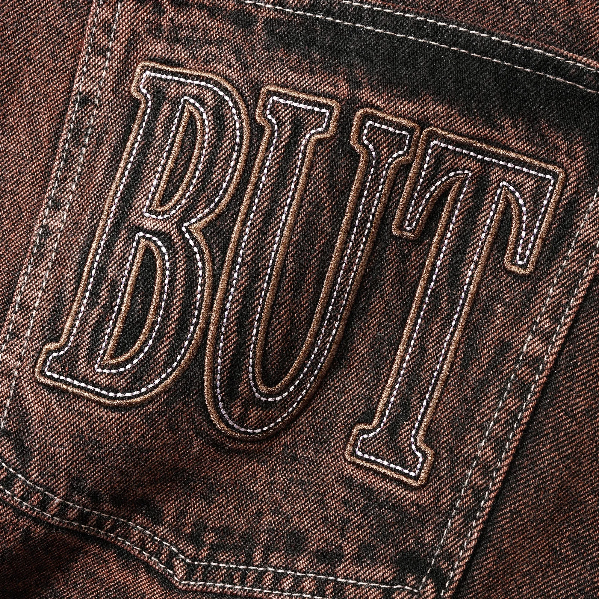 Brown acid wash denim jeans with Butter Goods applique